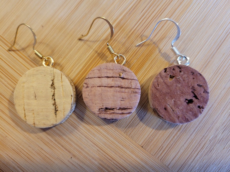 May include: Three pairs of cork earrings with gold and silver hooks. The cork is natural and has a light brown color.