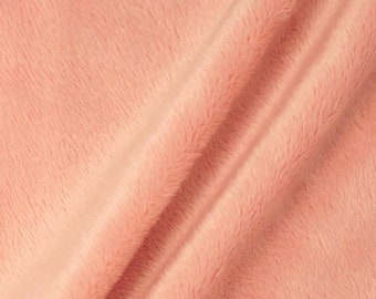 Könnte beinhalten: Nahaufnahme eines weichen, pfirsichfarbenen Stoffes mit einer flauschigen Textur. Der Stoff ist so gefaltet, dass die Textur und Farbe sichtbar sind.