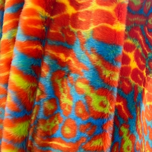 May include: Close-up of a colorful faux fur fabric with a tie-dye pattern in shades of orange, yellow, blue, and green.