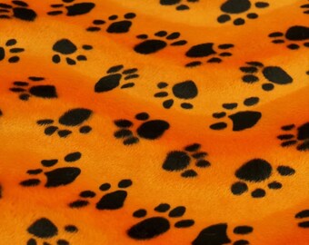 Könnte beinhalten: Orangener Stoff mit einem schwarzen Pfotenabdruckmuster. Der Stoff hat eine flauschige Textur.