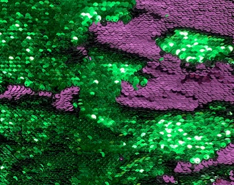 Könnte beinhalten: Nahaufnahme eines Stoffes mit grünen und violetten Pailletten. Die Pailletten sind in einem zufälligen Muster angeordnet und erzeugen einen schimmernden Effekt.