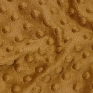 May include: A close-up of a brown minky fabric with a textured, dotted pattern. The fabric is soft and plush, perfect for blankets, throws, or other home decor projects.