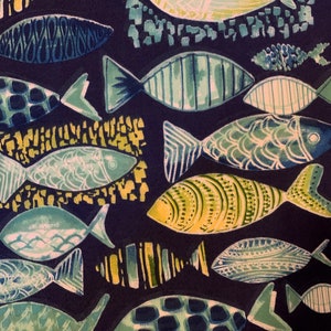 May include: A navy blue fabric with a repeating pattern of stylized fish in various shades of blue, green, and yellow. The fish have different patterns, including stripes, dots, and swirls.
