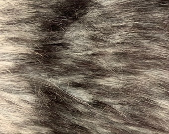 Könnte beinhalten: Nahaufnahme eines weichen, flauschigen, schwarz-weißen Kunstpelzes. Das Fell ist lang und fließend und erzeugt eine luxuriöse und gemütliche Textur.