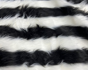 Könnte beinhalten: Schwarz-weiß gestreiftes Kunstfellgewebe. Der Stoff hat einen langen Flor und ist weich im Griff.