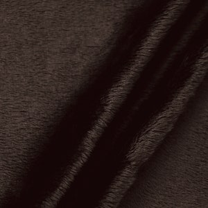 May include: Close-up of a dark brown faux fur fabric with a soft, plush texture. The fabric is folded in half, showing the pile of the fur.