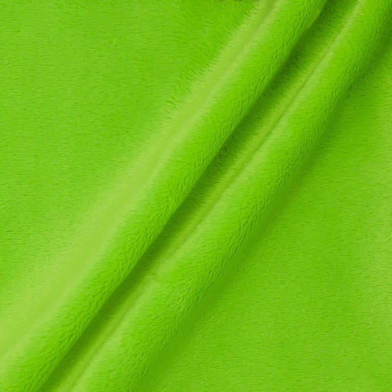 Puede incluir: Primer plano de una tela peluda de color verde brillante. La tela es suave y mullida, con una textura sutil.