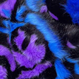 Puede incluir: Primer plano de un textil de piel sintética con un patrón llamativo. El diseño presenta vibrantes acentos de piel azul y púrpura sobre un fondo negro. La piel tiene un aspecto suave y texturizado, creando una superficie visualmente dinámica.