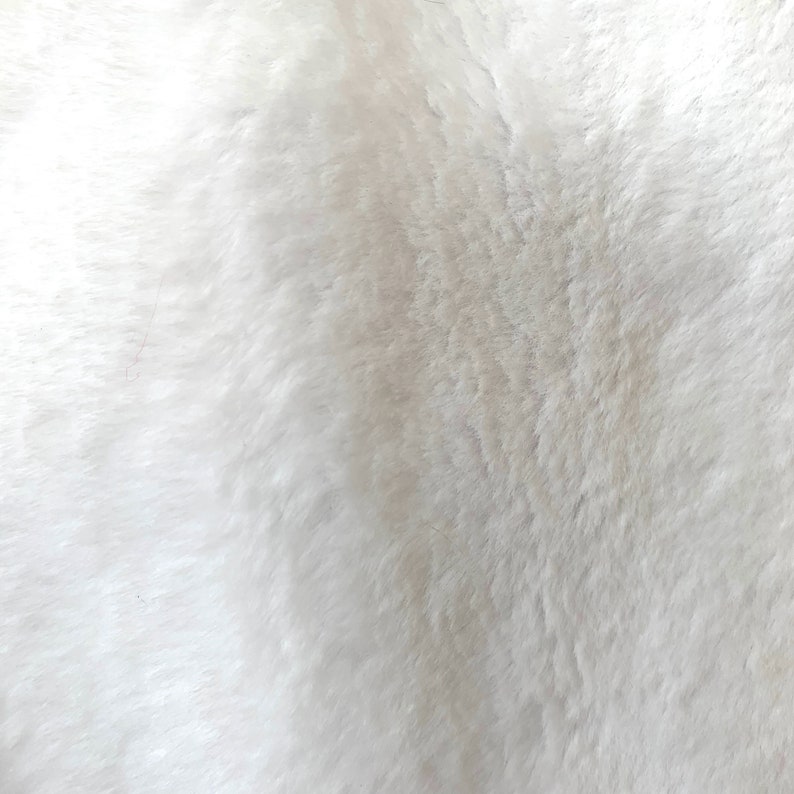 May include: White faux fur fabric with a soft, fluffy texture.