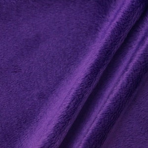 Puede incluir: Primer plano de una tela suave y afelpada de un tono morado intenso. La tela tiene una textura sutil y un ligero brillo.