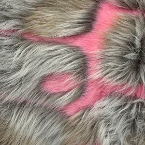 May include: Close-up of a grey and brown fur fabric with pink paint splatter. The paint is in a random pattern and creates a unique design.