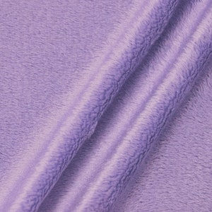 May include: A close-up of a soft, plush fabric in a light purple color. The fabric has a fuzzy texture and is folded in a way that shows the depth of the pile.