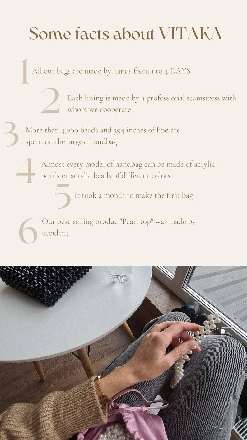May include: A close-up of a hand holding a strand of white pearls. The pearls are strung on a thin wire. The hand is wearing a brown sweater and a gold bracelet. The background is a blurry image of a table and a window.