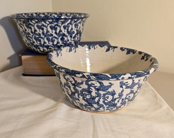 May include: Two blue and white ceramic mixing bowls with a speckled pattern. The bowls are nested together on a white surface.