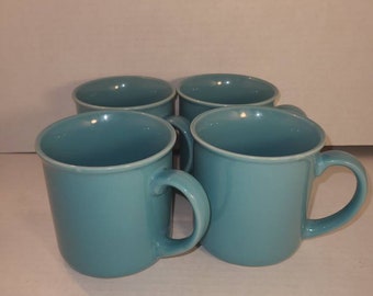 May include: Set of four teal blue ceramic mugs. The mugs have a simple design and are perfect for everyday use.