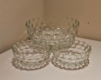 May include: A set of clear glass bowls with a geometric, diamond-like pattern. The set includes one large bowl and three smaller bowls, all with a textured surface. The bowls are arranged on a white surface.