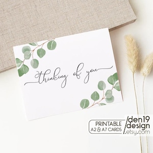 May include: A white card with the words "Thinking of you" in elegant script, accented with watercolor eucalyptus leaves. The card is part of a printable A2 & A7 card set.