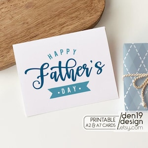 May include: A white card with the text "HAPPY Father's DAY" in blue script. The card has a blue banner with the word "DAY" on it. The card is next to a wrapped gift with a string bow. The card also has the text "PRINTABLE A2 & A7 CARDS" and "den19 design etsy.com".