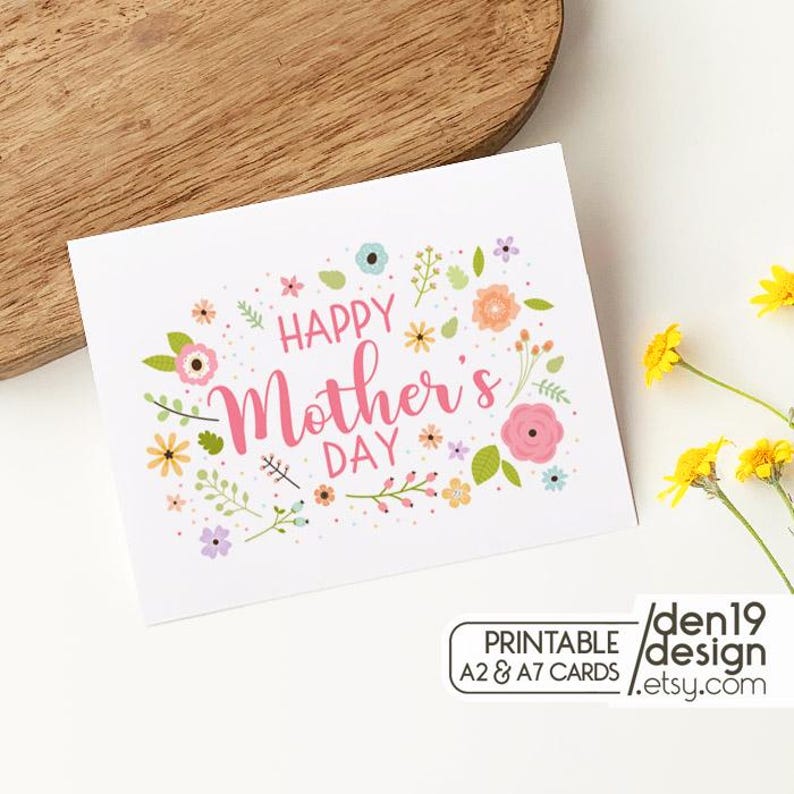 May include: A white greeting card with the text "HAPPY Mother's DAY" in pink script, surrounded by colorful floral illustrations. The card includes the text "PRINTABLE A2 & A7 CARDS" and the Etsy shop name.