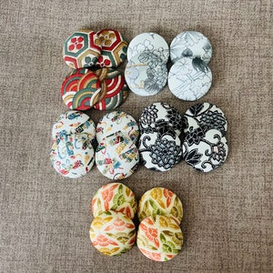 May include: A set of 10 round fabric buttons with various Japanese-inspired patterns. The buttons are in shades of black, white, red, green, and gold.