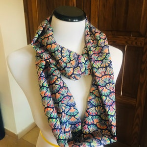 Puede incluir: Una bufanda infinita azul marino con un estampado de plumas de pavo real de colores.