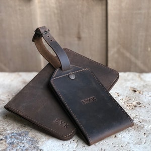May include: A set of brown leather travel accessories, including a wallet and luggage tag. The wallet and tag are embossed with the initials "EYK". The luggage tag has a strap with a buckle.