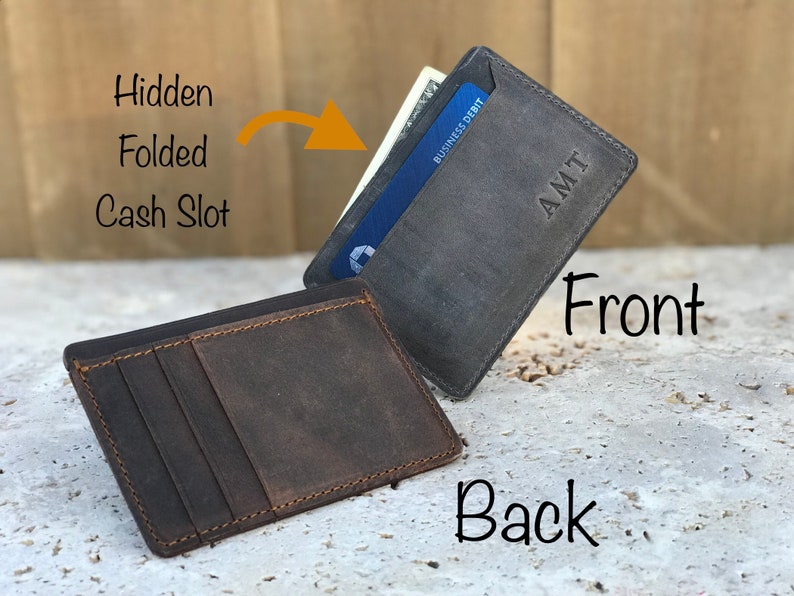 May include: A brown leather wallet with a hidden cash slot and a separate card slot. The front of the wallet is grey and has the initials "AMT" embossed on it.