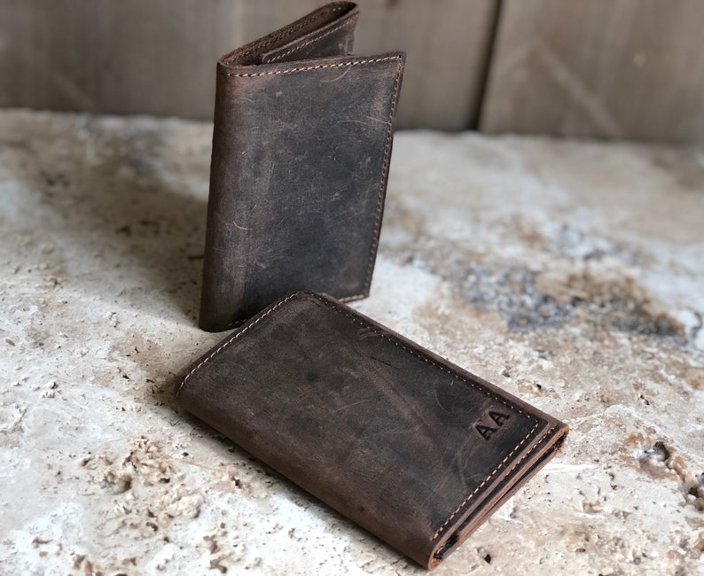 May include: Two brown leather wallets, one with the initials "AA" embossed on the front.