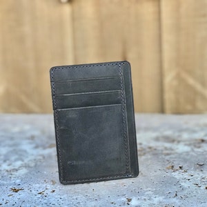 May include: A black leather wallet with multiple card slots and a single billfold. The wallet is made of distressed leather with a subtle texture.