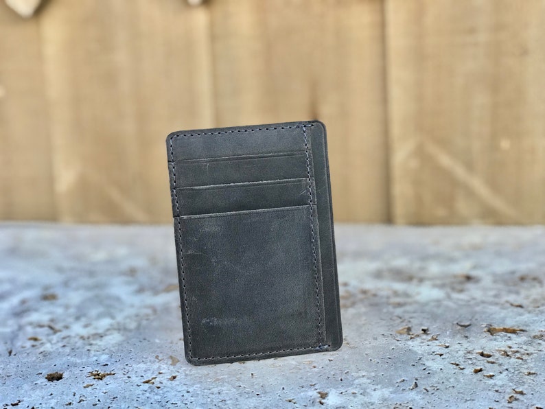 May include: A black leather wallet with multiple card slots and a single billfold. The wallet is made of distressed leather with a subtle texture.