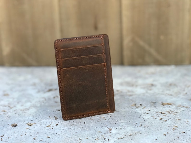 May include: A brown leather wallet with multiple card slots. The wallet has a distressed look and is made of high-quality leather.