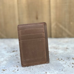 May include: A brown leather wallet with multiple card slots. The wallet has a minimalist design and is made of high-quality leather.