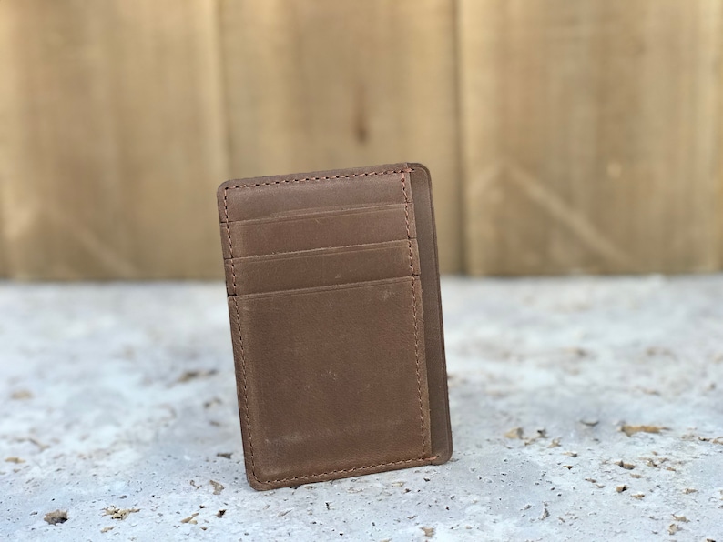 May include: A brown leather wallet with multiple card slots. The wallet has a minimalist design and is made of high-quality leather.