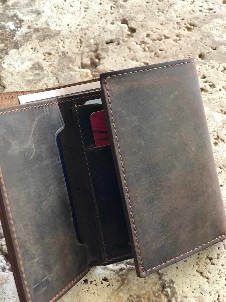 May include: A brown leather wallet with multiple card slots and a billfold. The wallet is open and shows the interior lining.