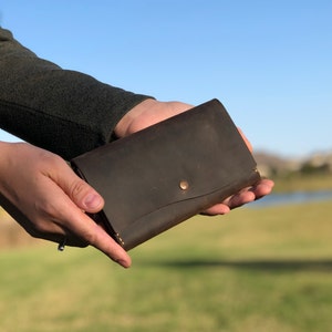 May include: A brown leather wallet with a single button closure.