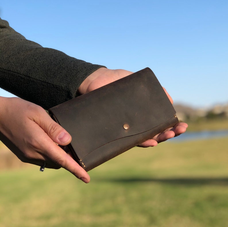 May include: A brown leather wallet with a single button closure.