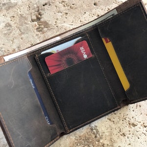 May include: A brown leather wallet with multiple card slots and a billfold. The wallet is open and shows a Discover card, a Chase Debit card, and a yellow card with the word "WMT" on it.