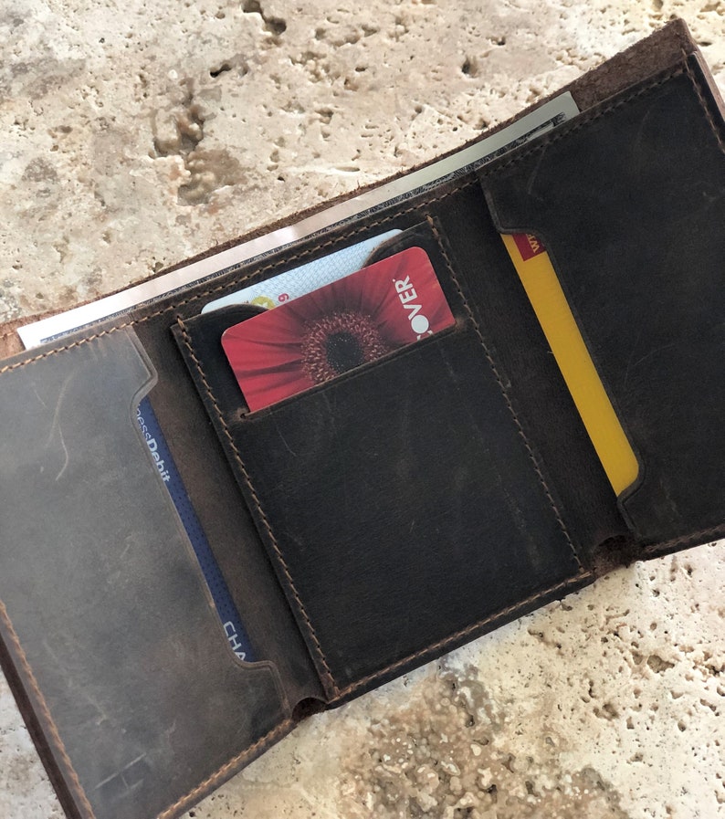 May include: A brown leather wallet with multiple card slots and a billfold. The wallet is open and shows a Discover card, a Chase Debit card, and a yellow card with the word "WMT" on it.
