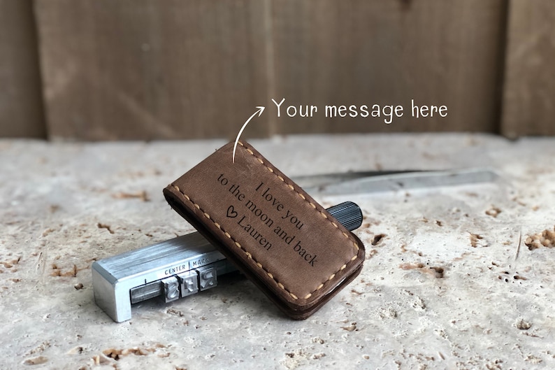 May include: Brown leather money clip with a stitched edge and engraved text: "I love you to the moon and back &hearts; Lauren".