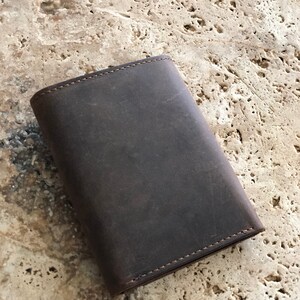 May include: A dark brown leather wallet with a stitched edge.