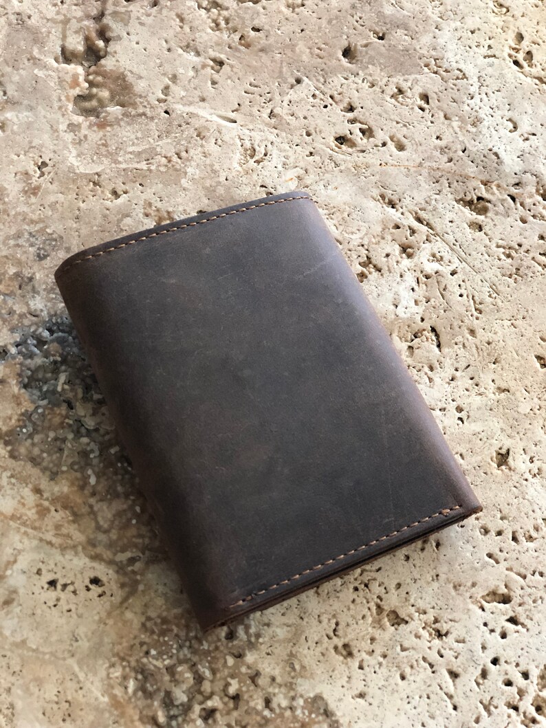 May include: A dark brown leather wallet with a stitched edge.