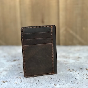 May include: A brown leather wallet with multiple card slots and a pocket for cash. The wallet has a distressed look and is stitched with brown thread.
