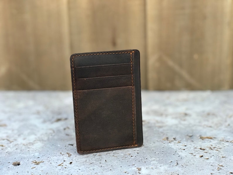 May include: A brown leather wallet with multiple card slots and a pocket for cash. The wallet has a distressed look and is stitched with brown thread.