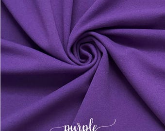Puede incluir: Tela morada con una textura suave y peluda. La tela está doblada y drapeada, mostrando su superficie lisa y la palabra "purple" escrita en cursiva blanca.