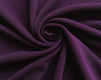 May include: Close-up of a deep purple textured fabric with a soft, crinkled appearance. The fabric is folded and twisted, creating a swirling pattern.