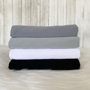 May include: Four fabric swatches stacked on top of each other. The top swatch is a light gray, the second swatch is a medium gray, the third swatch is white, and the bottom swatch is black.