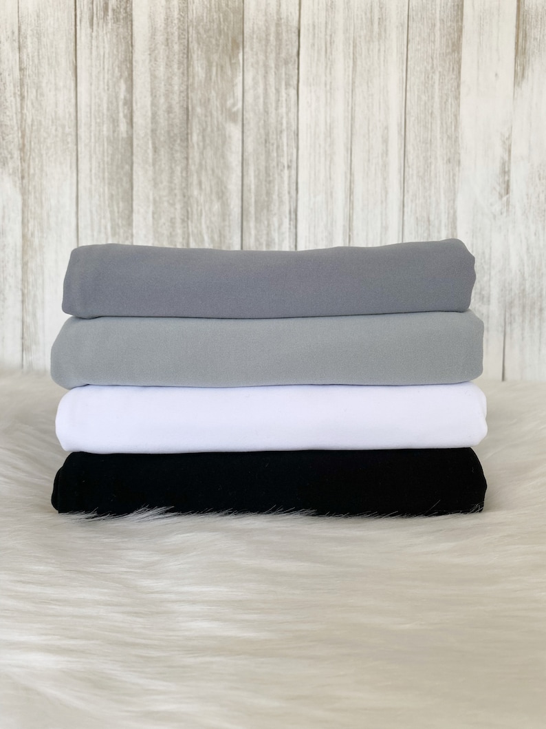 May include: Four fabric swatches stacked on top of each other. The top swatch is a light gray, the second swatch is a medium gray, the third swatch is white, and the bottom swatch is black.
