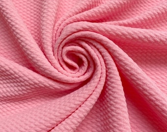 May include: A close-up of a pink textured fabric. The fabric is soft and has a waffle-like texture.