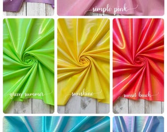 May include: A collection of fabric swatches in various colors, including lavender, pink, green, yellow, red, turquoise, and periwinkle. Each swatch is labeled with a color name in cursive script. The fabric has a shiny, iridescent finish.
