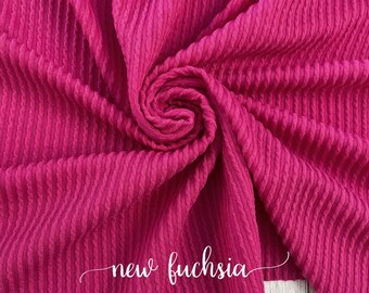 May include: A close-up of a bright fuchsia ribbed fabric. The fabric is folded and draped, showing its texture. The text "new fuchsia" is written in white cursive on the fabric.